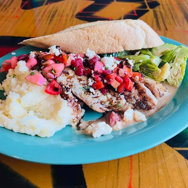Grilled fish with red relish, mashed potatoes, and a side salad on a blue plate.