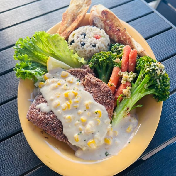 Keegan's Seafood Grille's fried fish with corn cream sauce, rice, broccoli, carrots, and garlic bread.